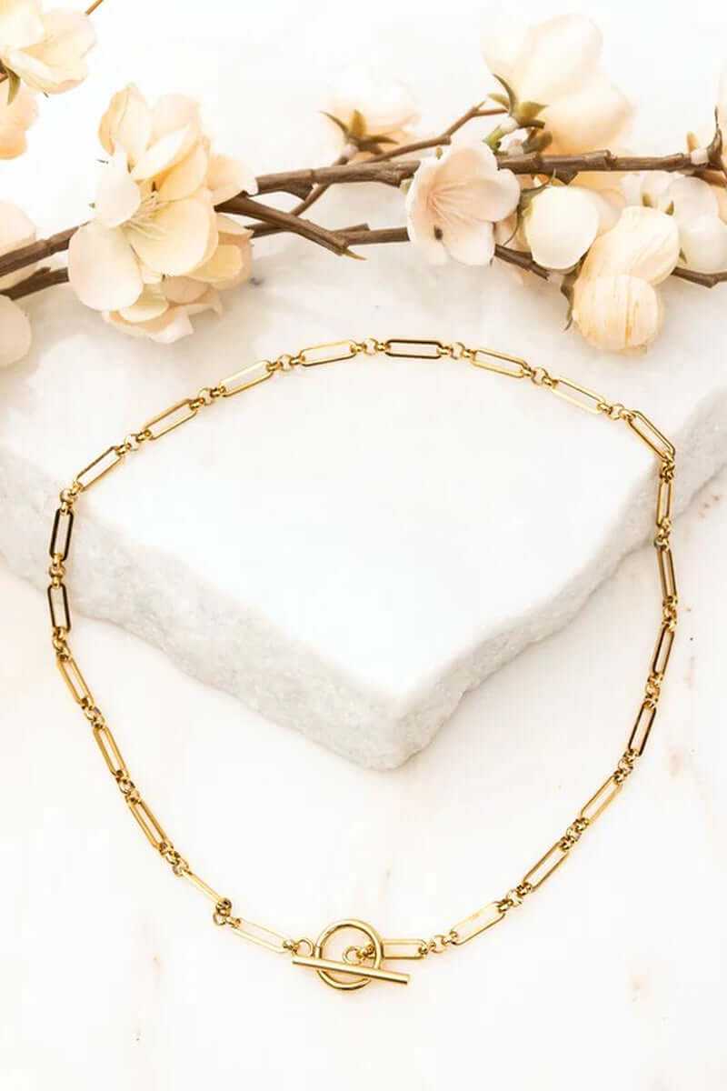 18K stainless steel toggle chain necklace on marble with floral accents, tarnish resistant, waterproof, gold plated.
