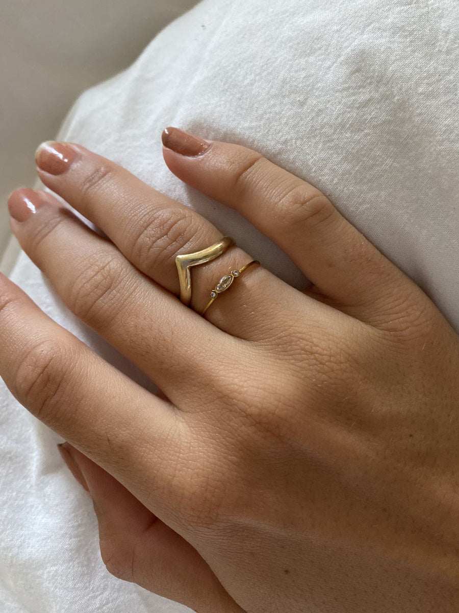 hand wearing delicate candy-colored pearl statement ring with gold plating on white fabric background