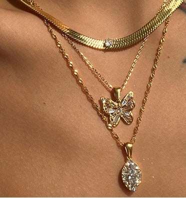 Three-layered gold necklace set featuring a butterfly pendant and teardrop charm on a model's neck.