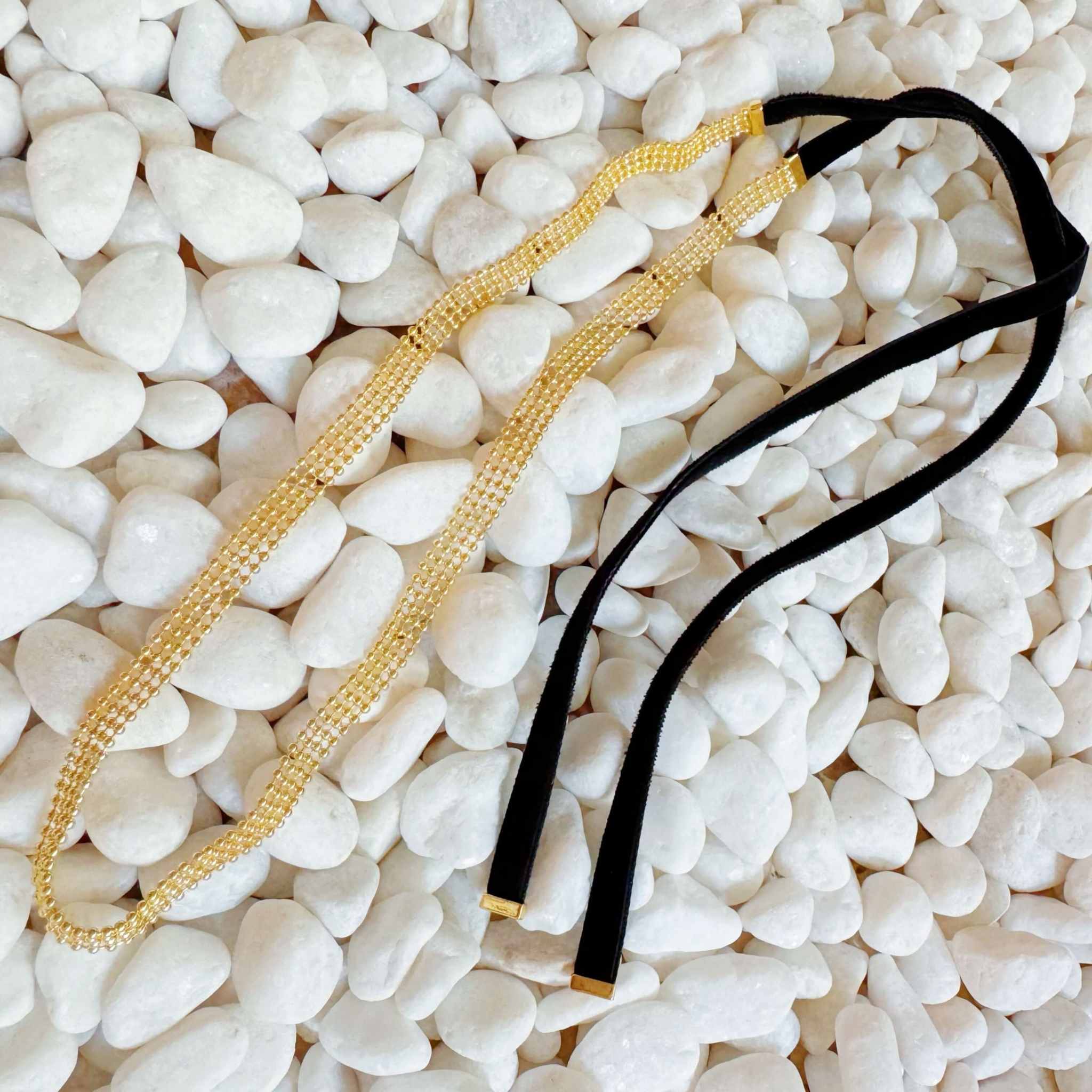 Adjustable gold tie back choker necklace with velvet ties, layered gold beads on a white pebble background.
