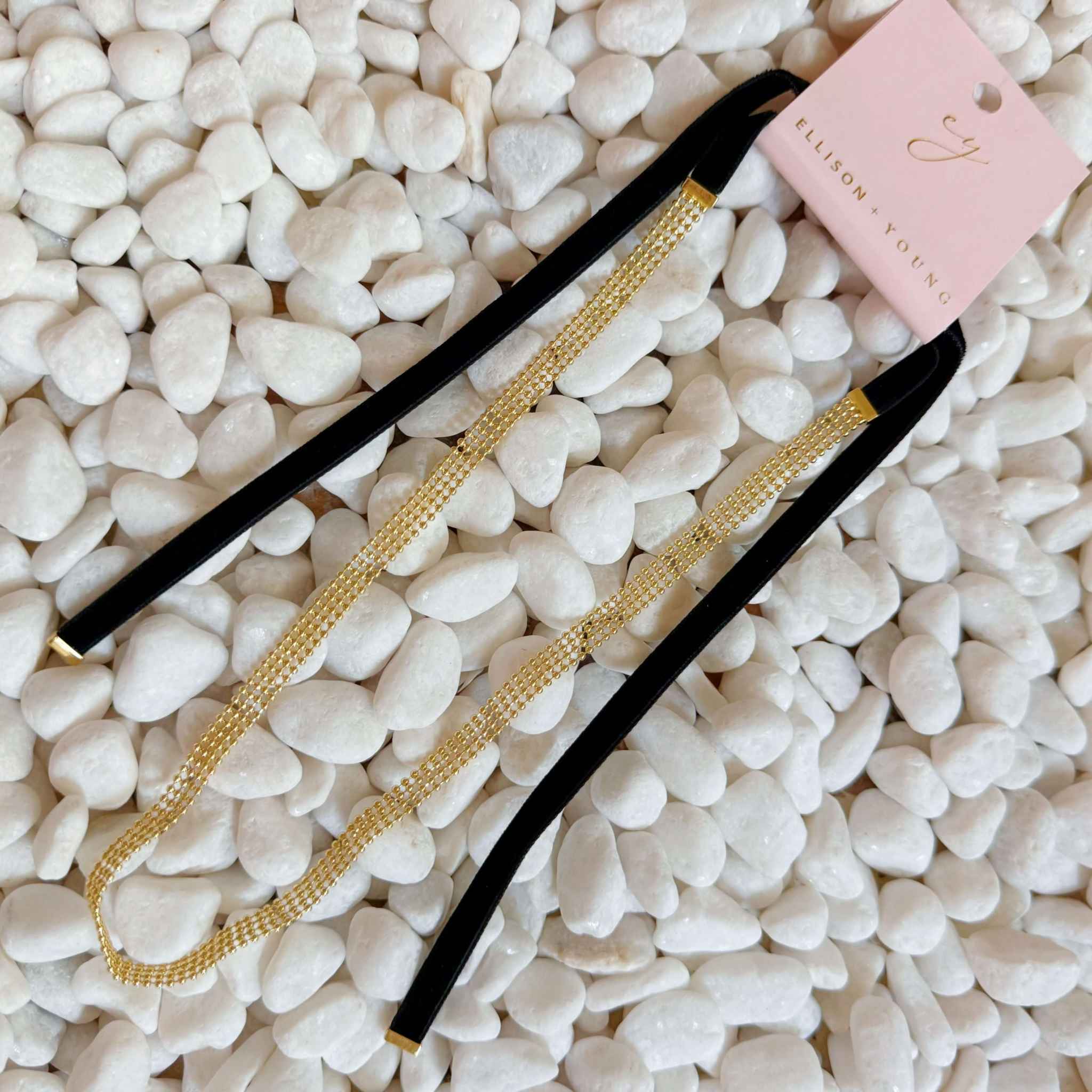 Adjustable Gold Tie Back Choker Necklace with velvet ties on white pebbles, showcasing versatile styling options.
