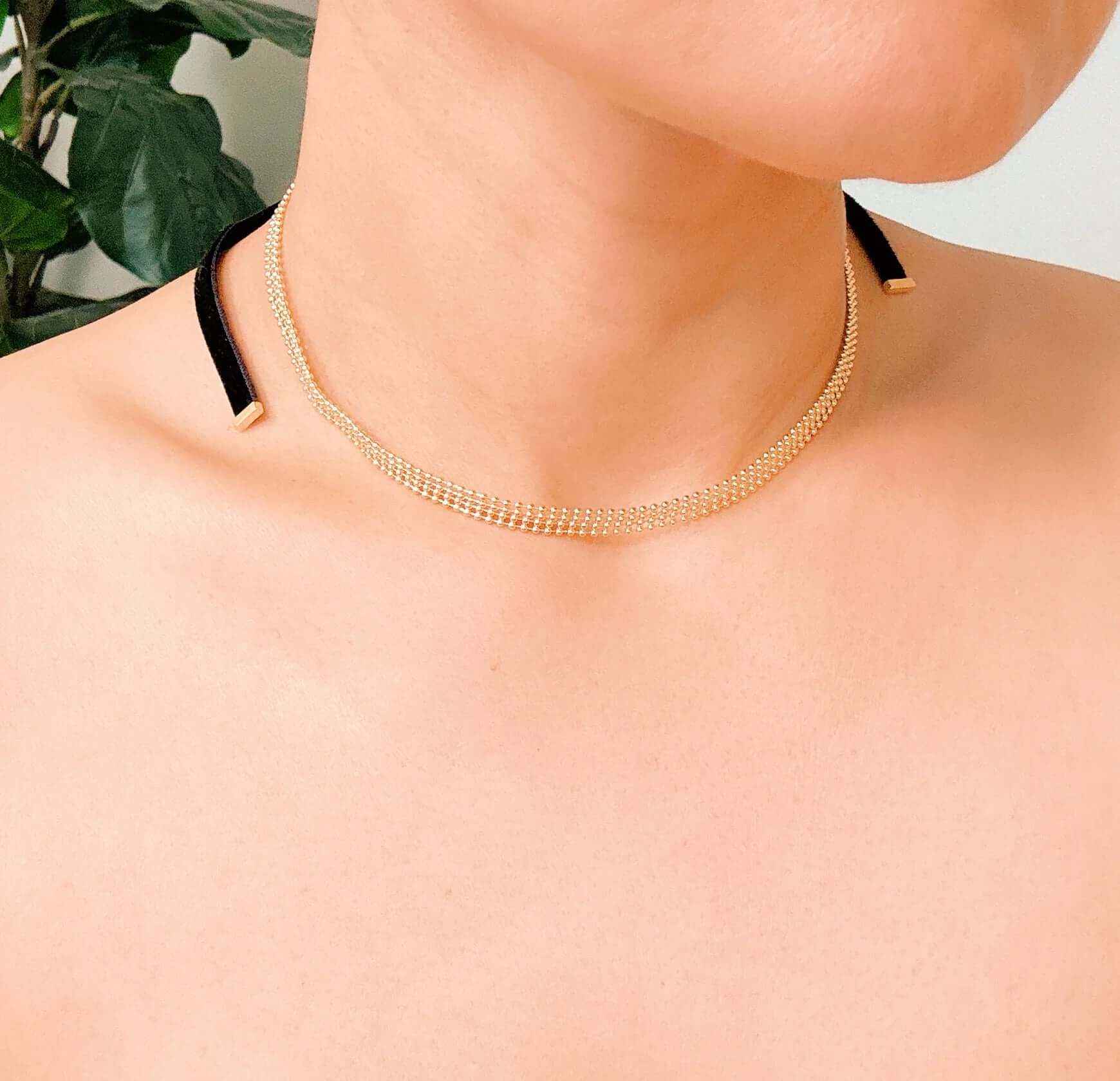 Adjustable gold tie back choker necklace featuring layered gold beads and velvety black ties for versatile styling.