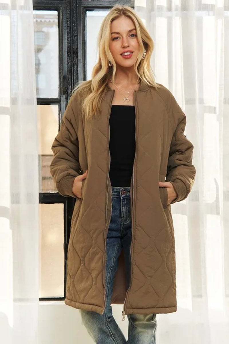 Woman wearing ADORA zip up long utility jacket in brown quilted fabric with front pockets, styled casually with jeans and black top