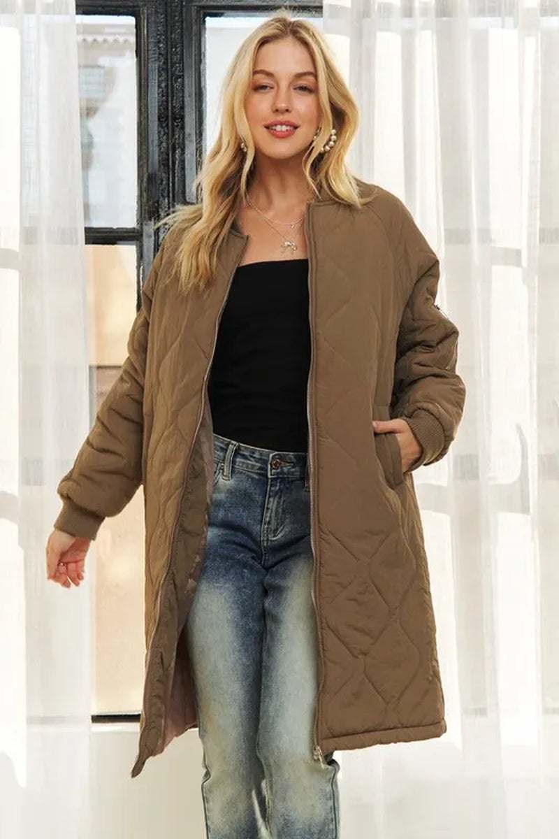 Woman wearing brown zip up long utility jacket with pockets over black top and blue jeans indoors