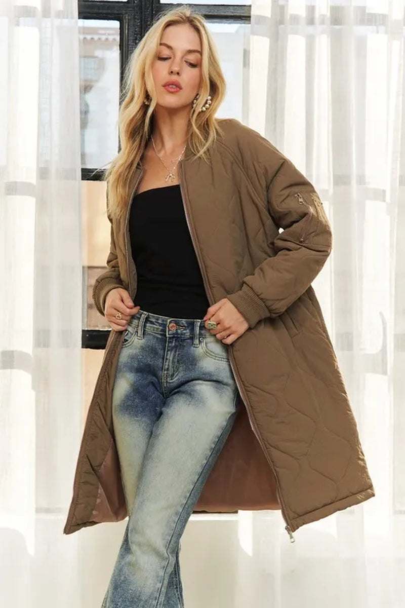Woman wearing brown zip up long utility jacket with pockets layered over black top and jeans