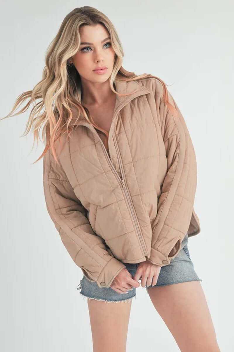Bebe puffer jacket in beige, featuring oversized silhouette and front zip closure, perfect for casual winter wear.