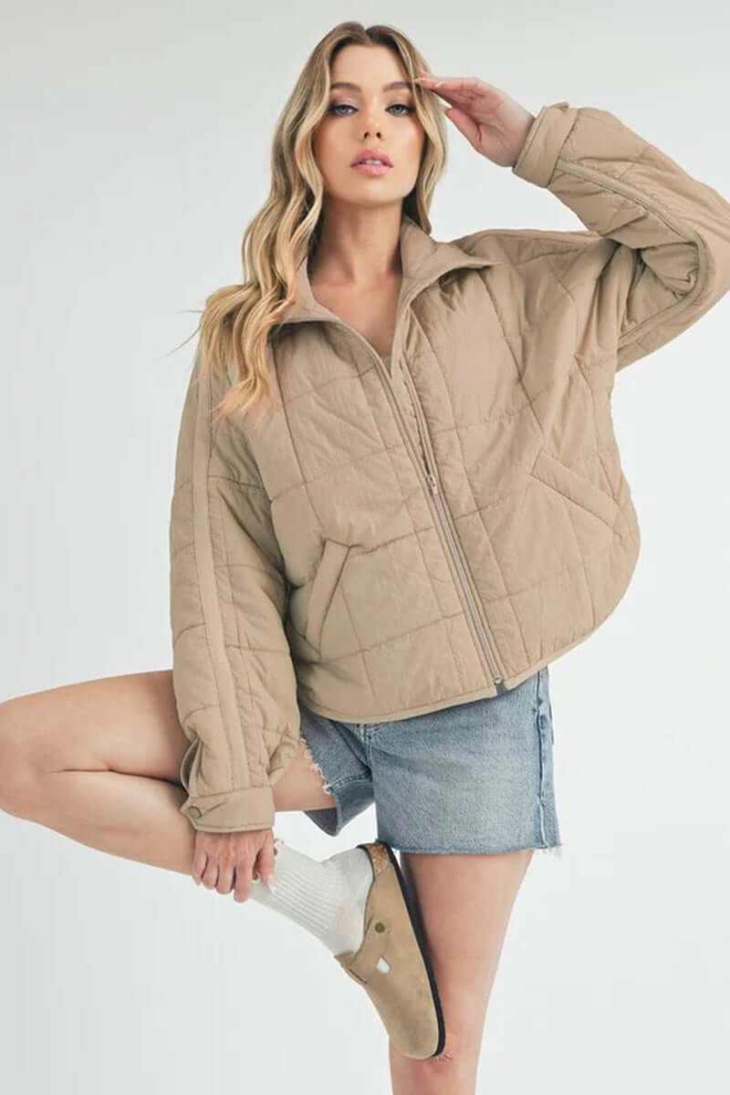 Bebe puffer jacket in beige, oversized style with front zip, paired with denim shorts and cozy socks.