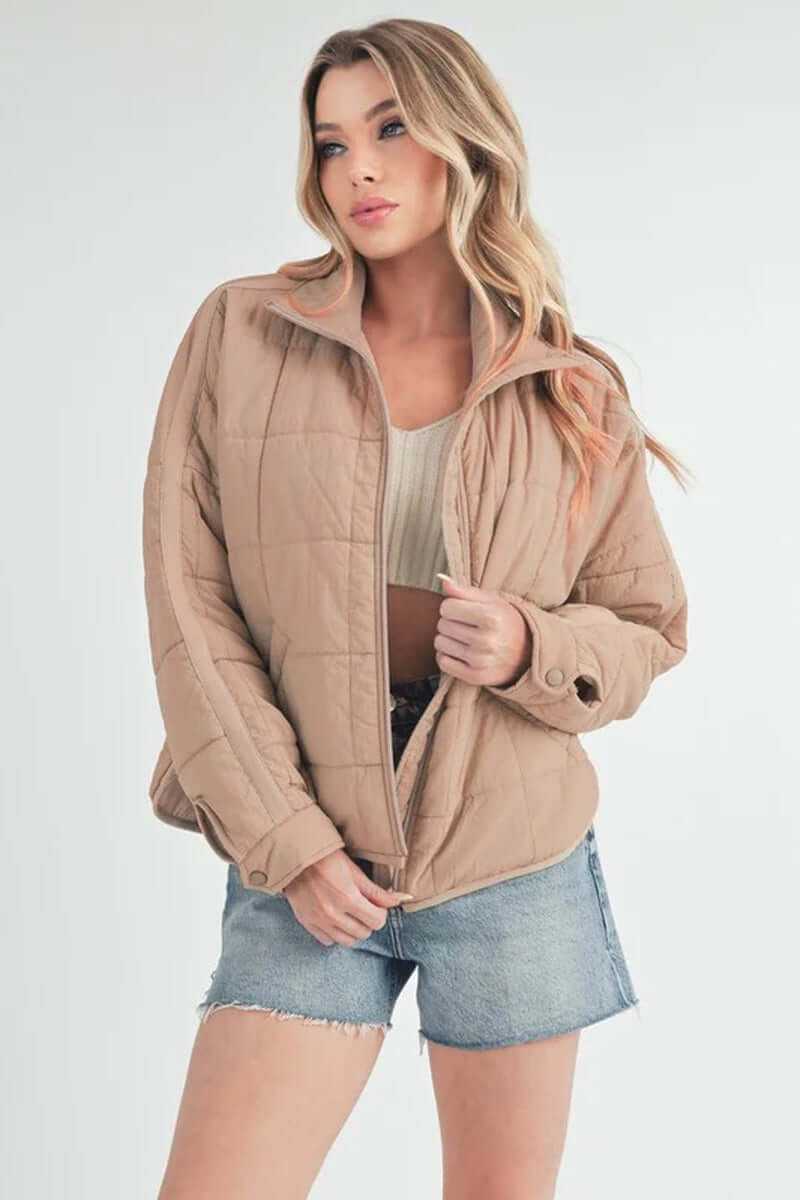 Bebe puffer jacket in beige, oversized with front zip, styled with denim shorts, perfect for casual outings.