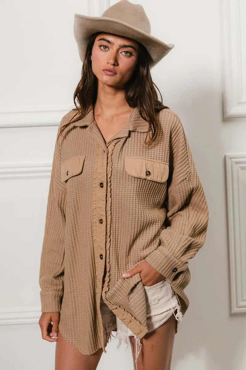 Model wearing a beige heavy waffle oversized shacket with buttoned pockets, paired with shorts and a stylish hat.