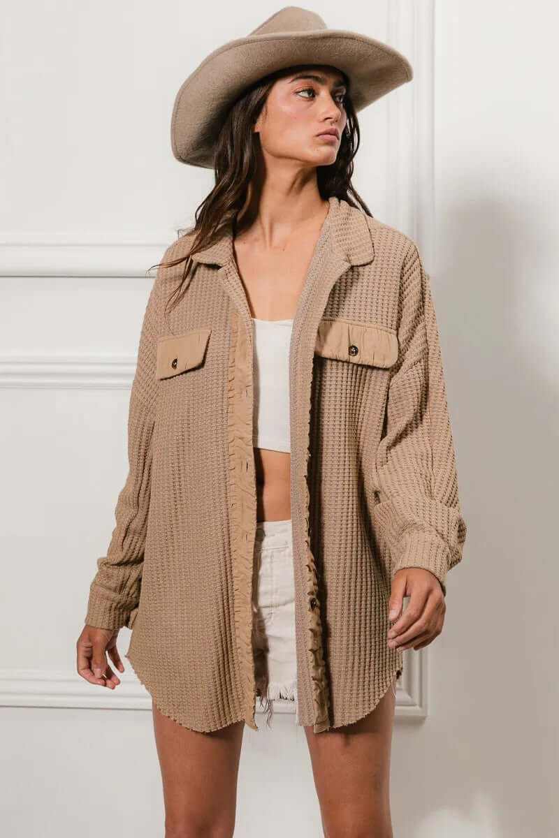 Model wearing a beige oversized heavy waffle shacket, styled with a white top and denim shorts, paired with a wide-brimmed hat.