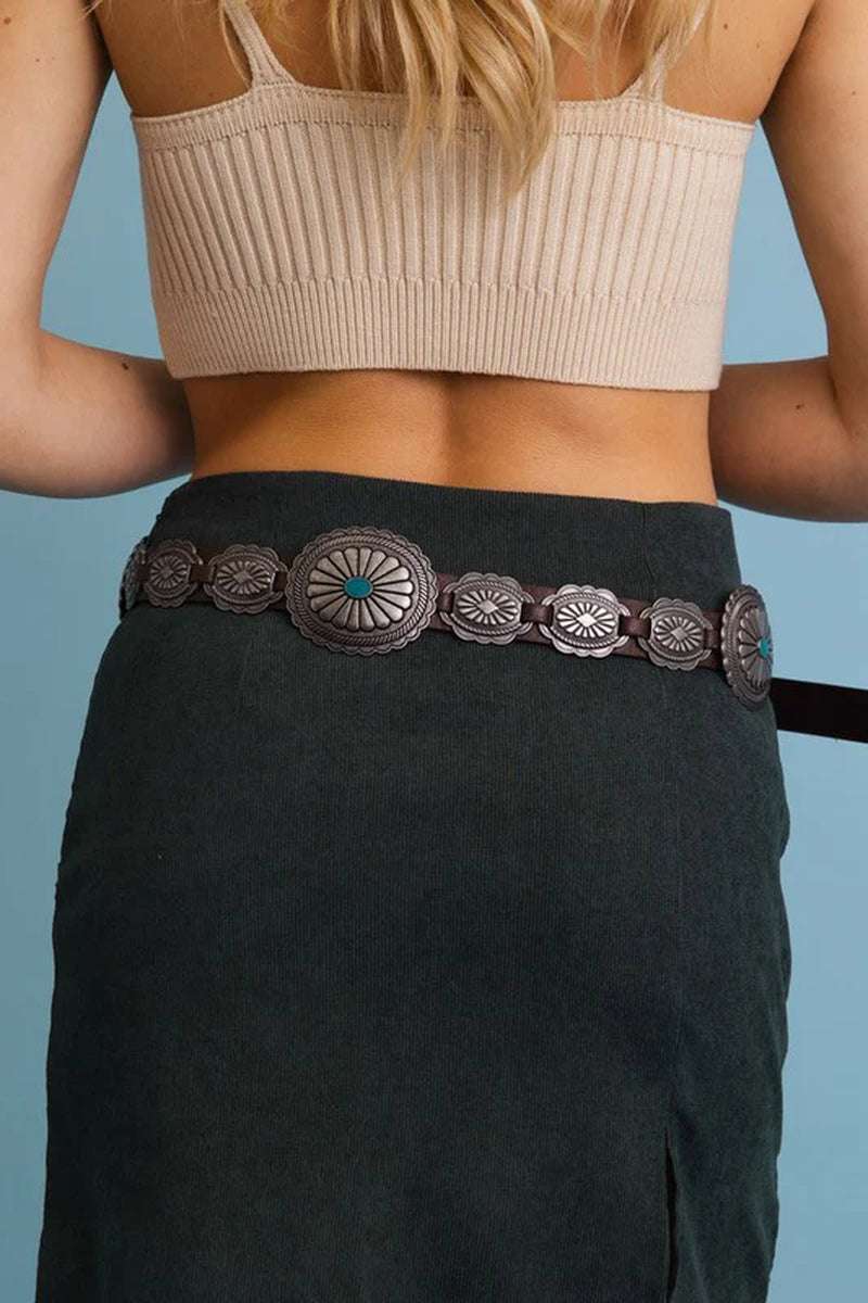 Back view of a woman wearing a Boho turquoise Western concho belt with intricate silver details, styled with a skirt.