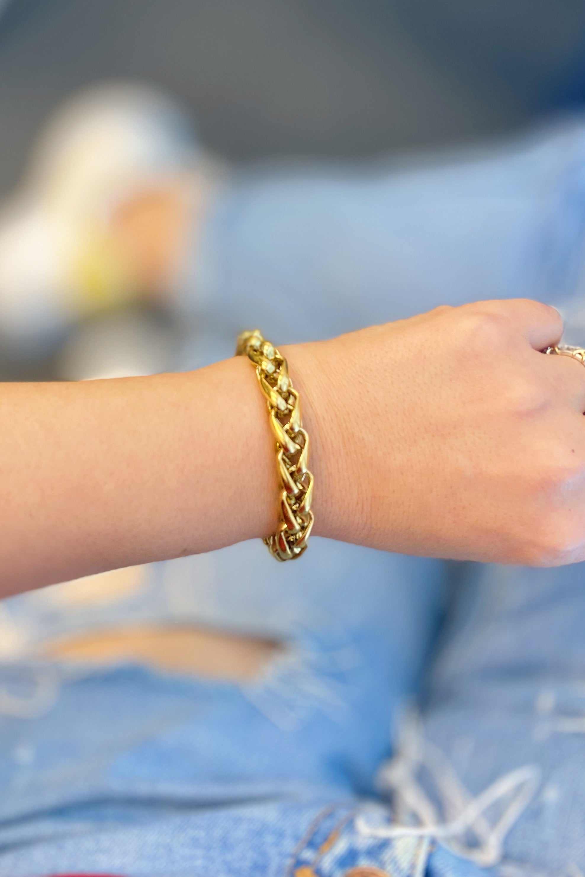 Bold and edgy gold chain bracelet worn on wrist, featuring small links, stylish and perfect for layering.