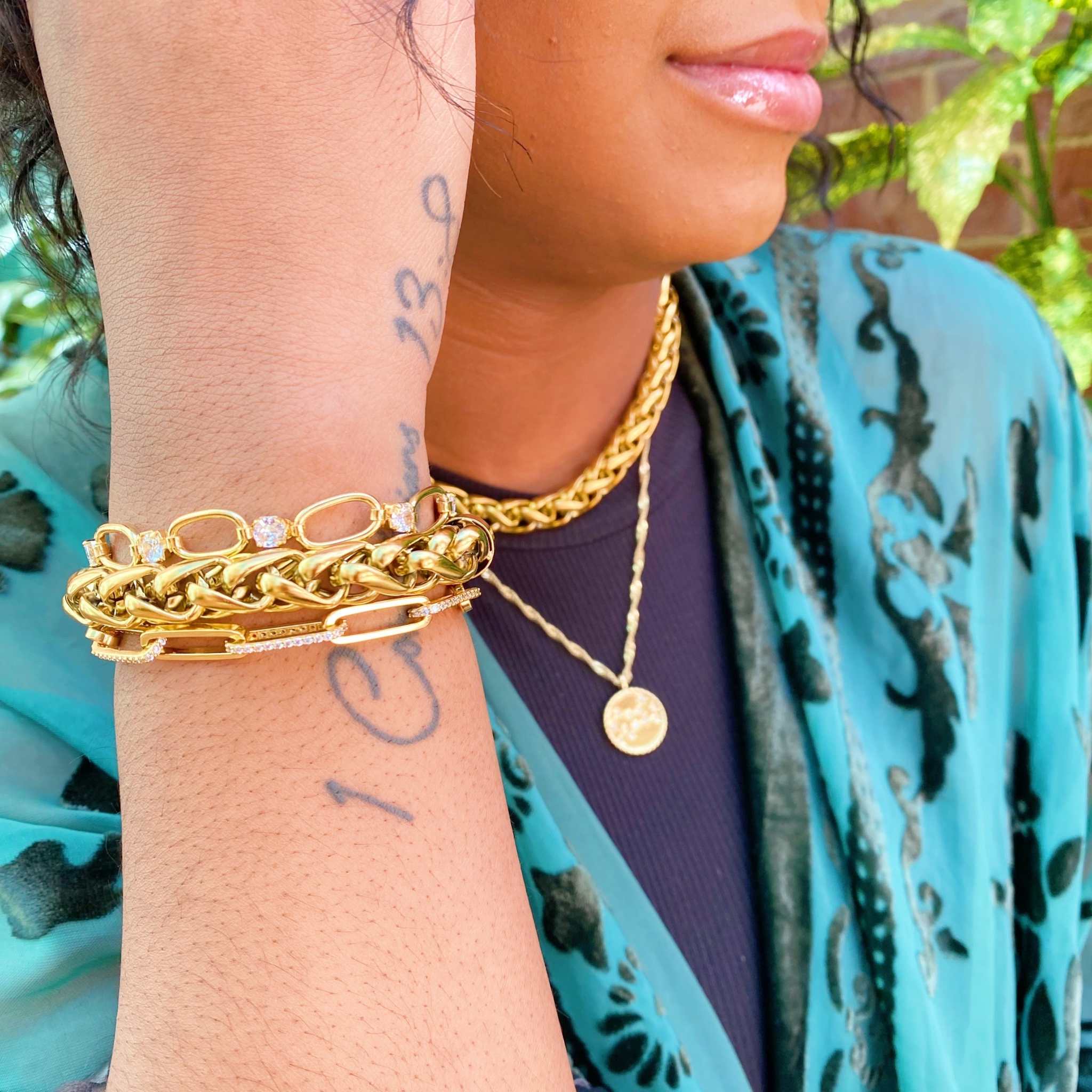 Bold and edgy fashion chain bracelet styled with gold necklace, showcasing chic design and layering options.