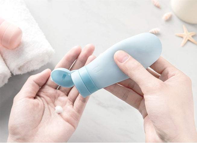 Blue silicone bottled travel cosmetics being squeezed for lotion use