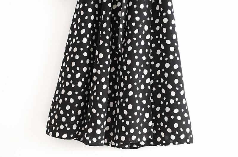Black chiffon dress with white polka dots, featuring a split wrap design and long sleeves.