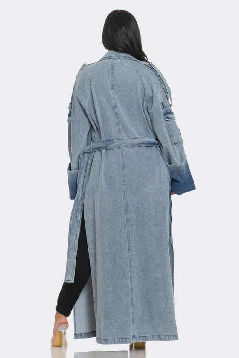 Back view of a woman wearing a classic longline denim trench coat with belted waist and oversized cuffs
