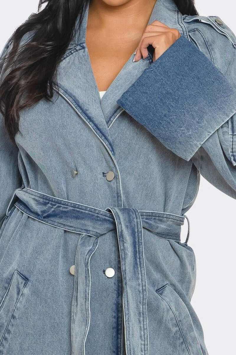 Woman wearing classic longline denim trench coat with belted waist and oversized cuffs