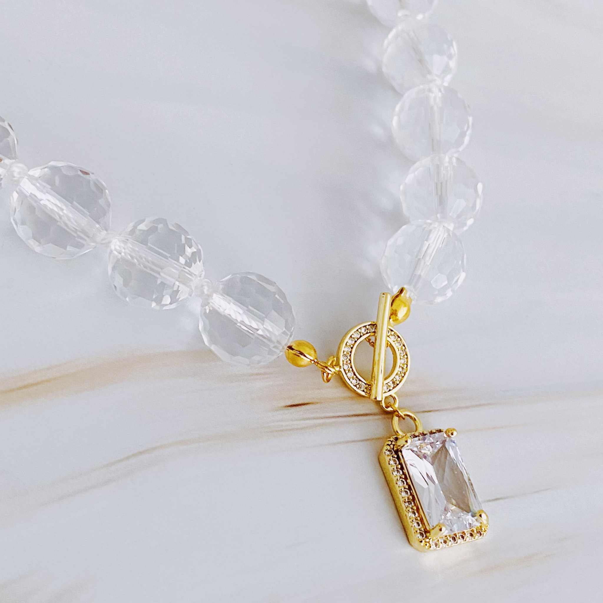 Clear crystal ball chain necklace with faceted glass beads and elegant gold toggle closure.