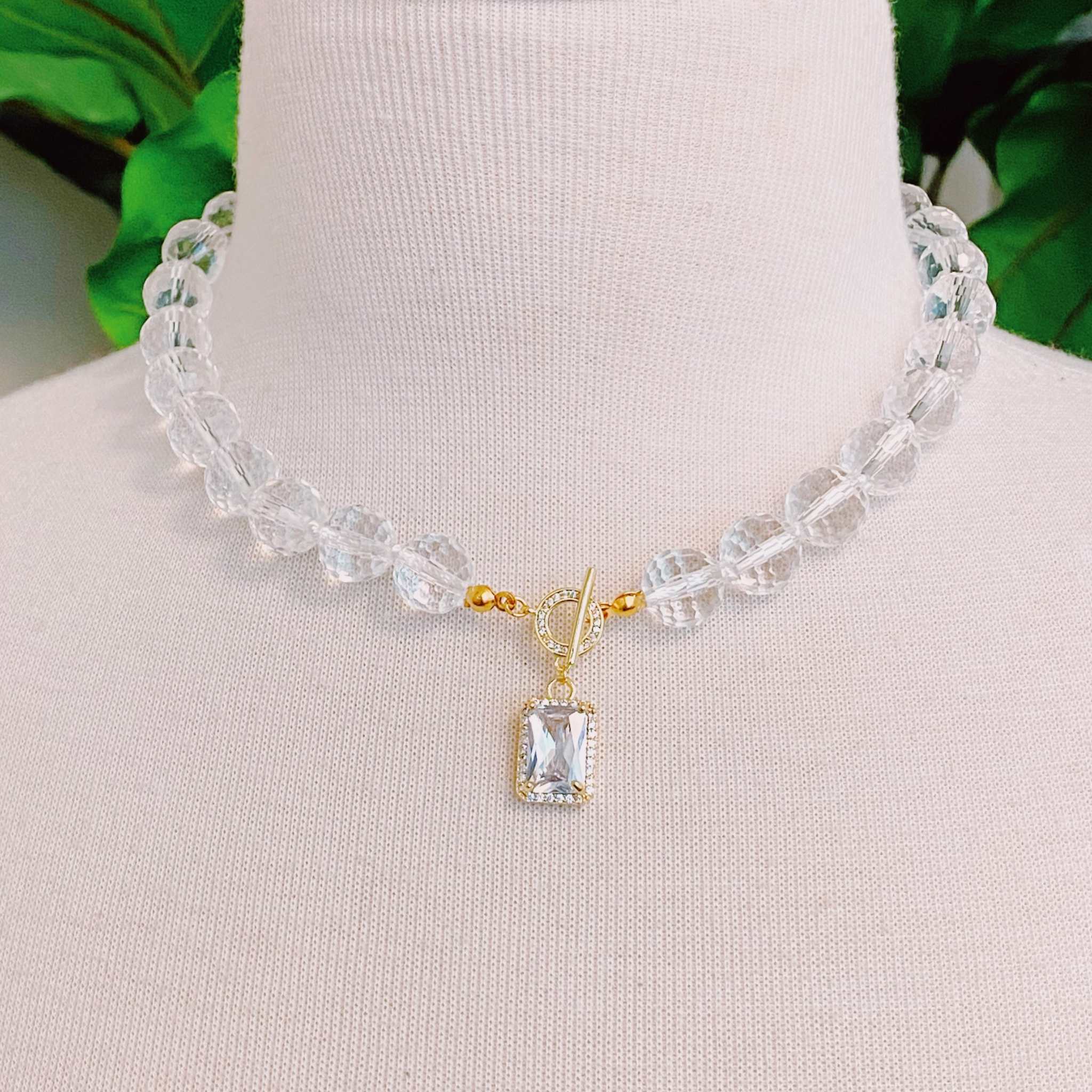 Clear crystal ball chain necklace with faceted glass beads and a gold pendant, elegant and versatile accessory.