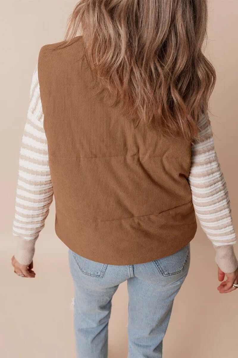 Back view of a woman wearing a brown corduroy puffer vest with striped sleeves, showcasing its cozy and stylish design.