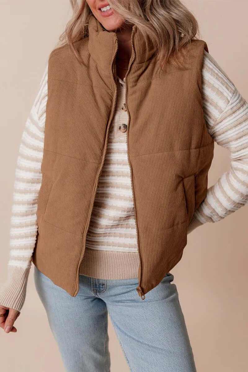 Coffee corduroy stand neck zipped puffer vest styled with a striped sweater and casual jeans.
