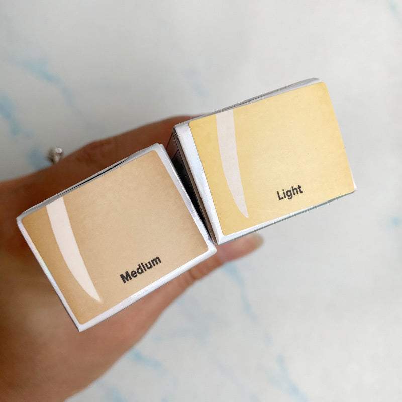 Two boxes of Matte Oil-Free Liquid Foundation in light and medium shades held in hand