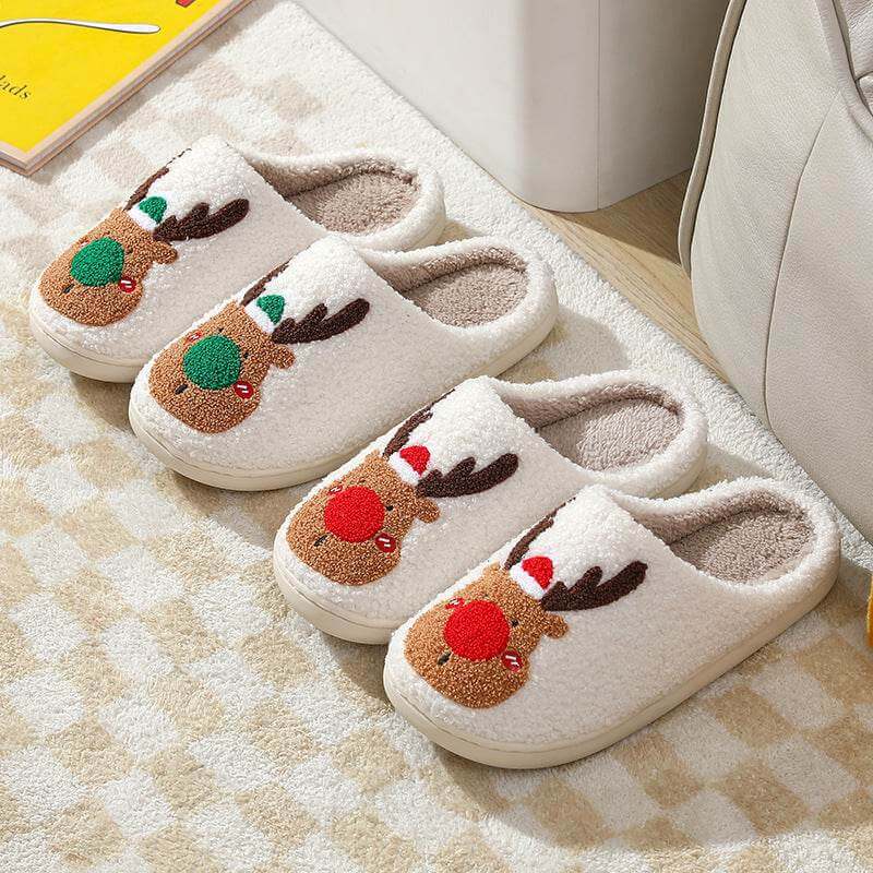 Pair of cozy winter home slippers with reindeer design and plush lining on checkered carpet