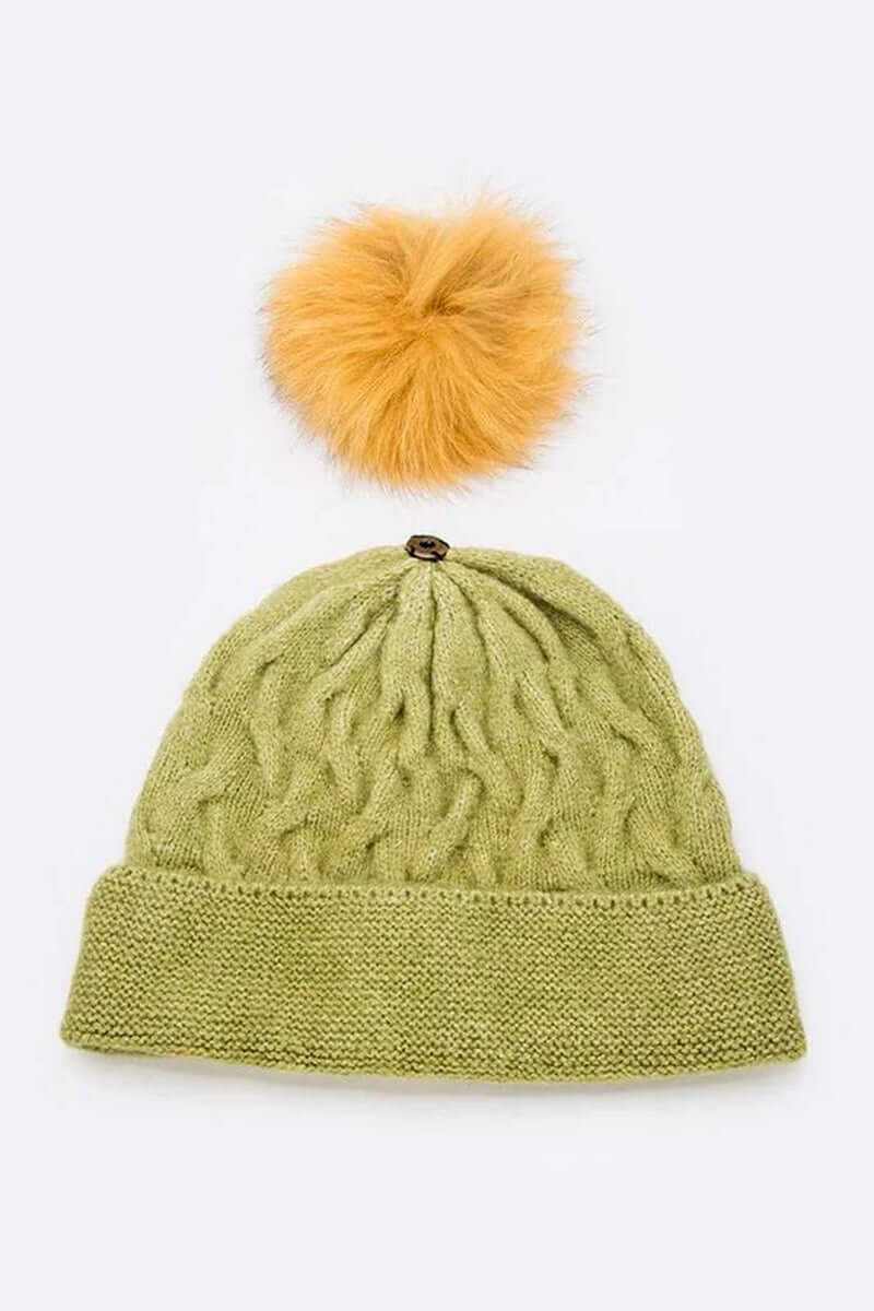 Cuffed slouchy beanie in olive green with a fluffy orange fur pom, perfect for winter style and warmth.