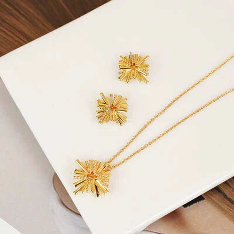 Dainty starburst gold plated jewelry set including earrings and pendant on a stylish background.