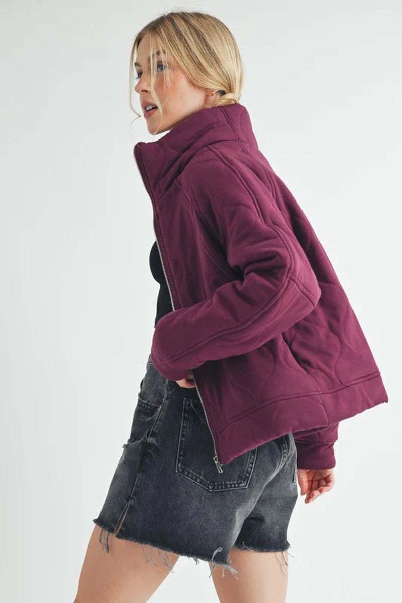 Model wearing a cozy Darla Quilted Jacket in burgundy, showcasing its oversized fit and stylish design.