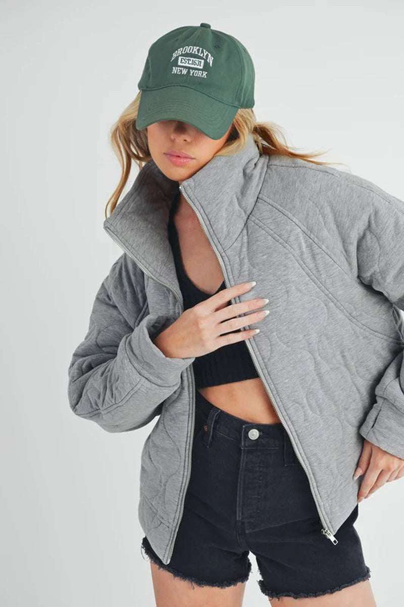 Model wearing a gray Darla Quilted Jacket with a relaxed fit, styled with a black top and shorts.