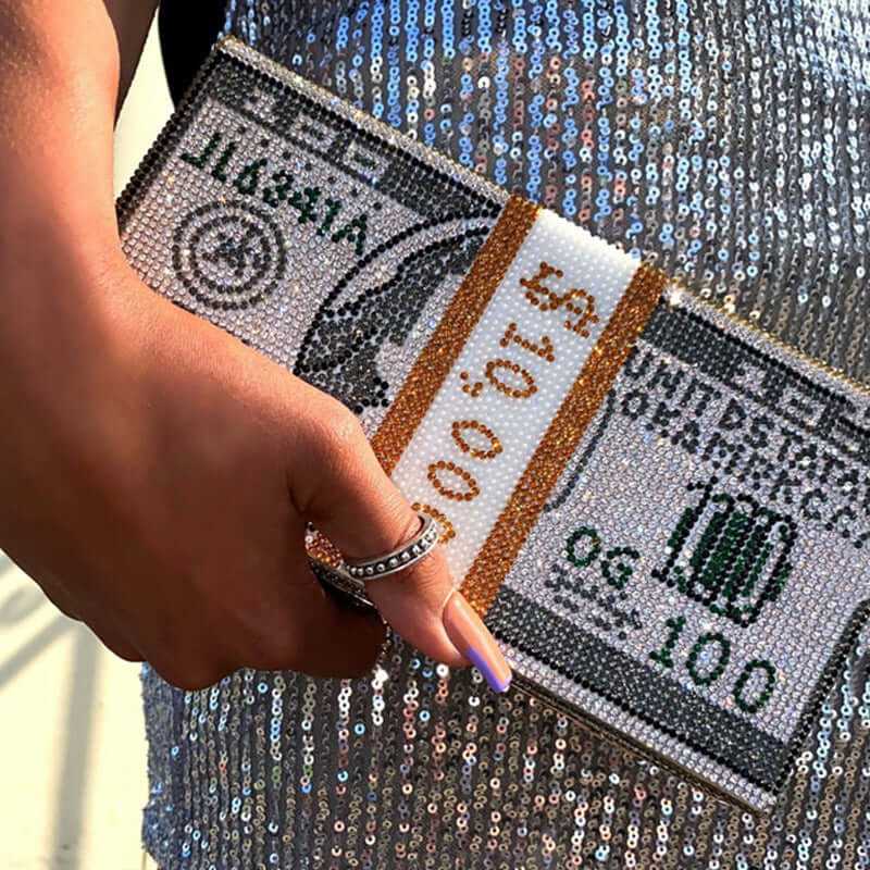 Hand holding a sparkling Diamond Crystal Dollar design luxury clutch purse adorned with rhinestones.