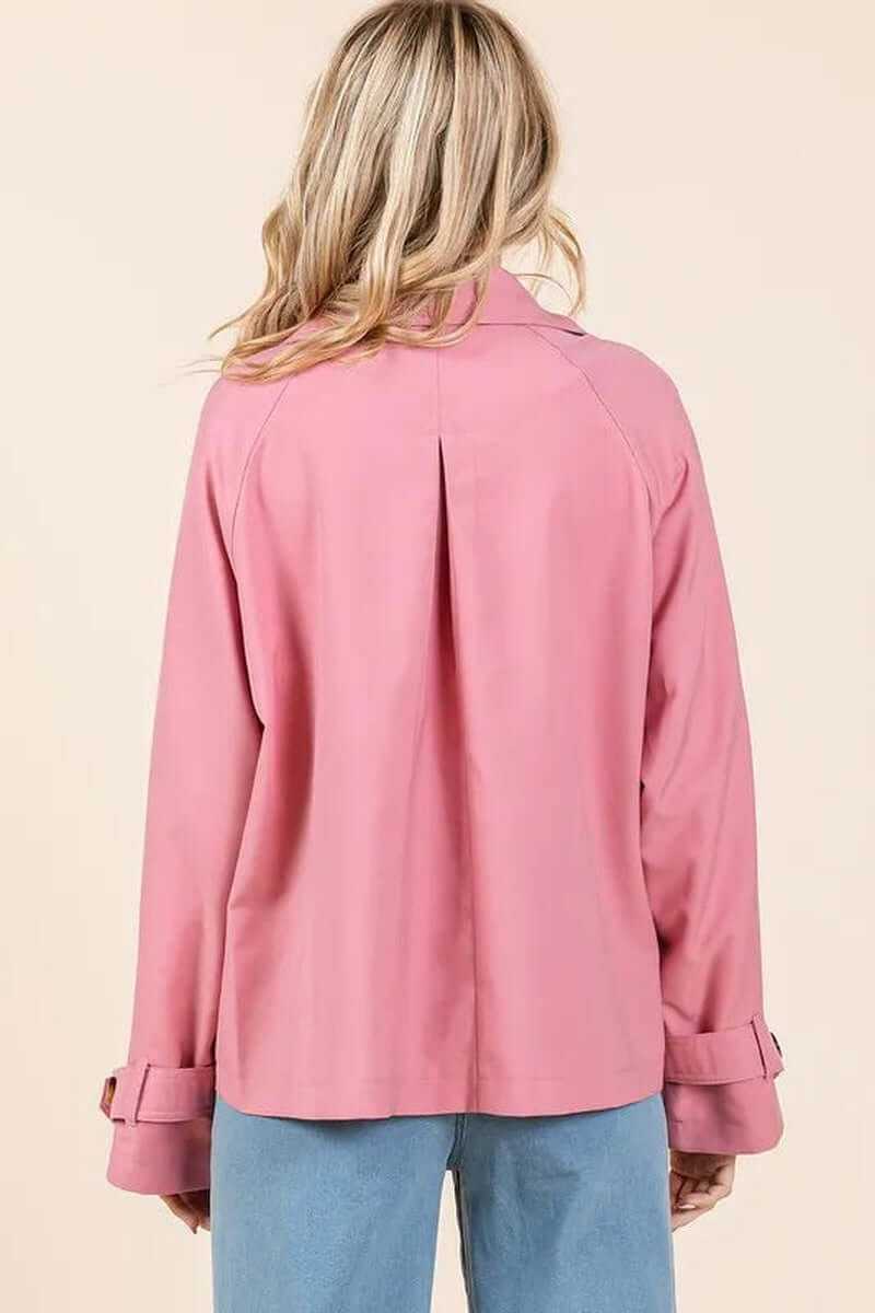 Back view of an elegant pink double-breasted trench coat with long sleeves and pleat detail, perfect for transitional weather.