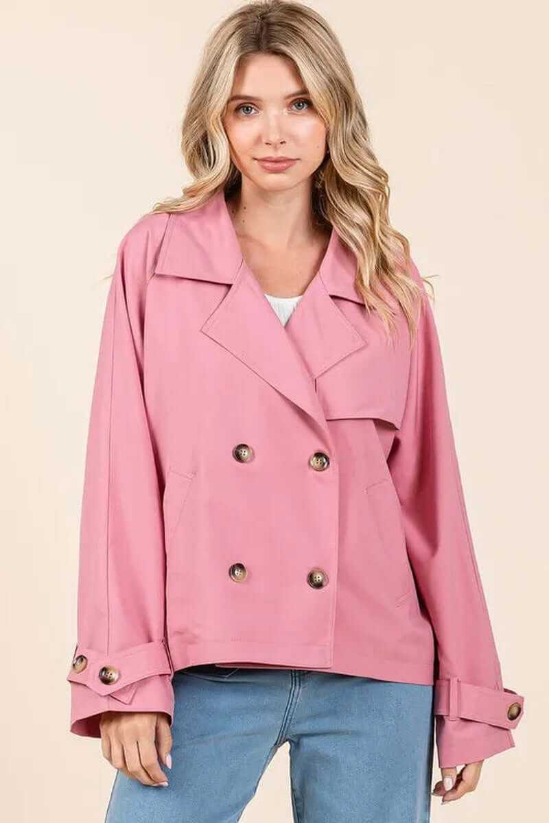 Elegant double-breasted trench coat in pink, featuring long sleeves and stylish buttons, perfect for transitional weather.