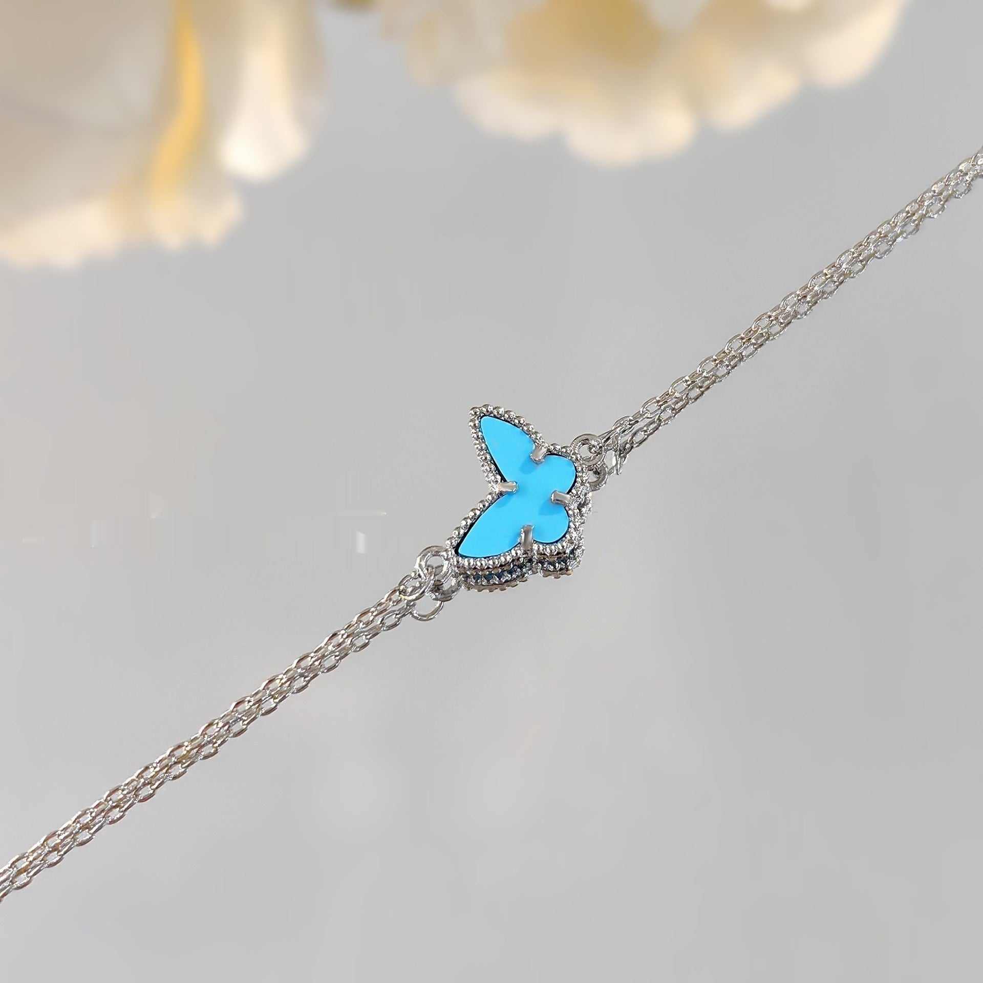 close-up of fashion blue turquoise butterfly bracelet with silver chain on gray background
