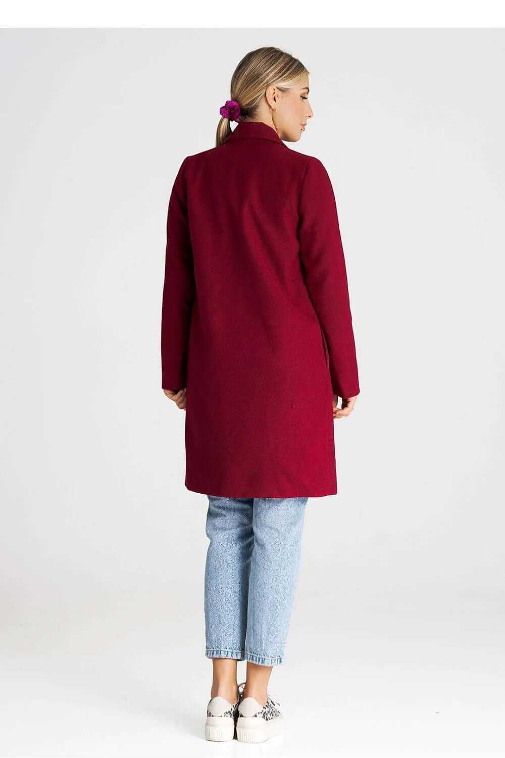 Back view of a woman wearing a burgundy Figl longline winter coat with a large collar and side pockets.