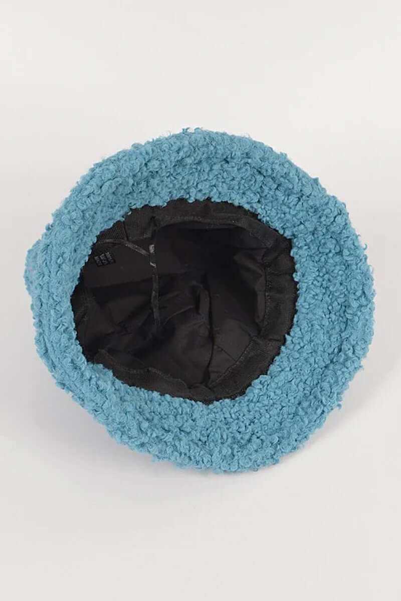 Inside view of a fluffy shearling faux fur bucket hat in aqua blue, showcasing its soft texture and cozy lining.