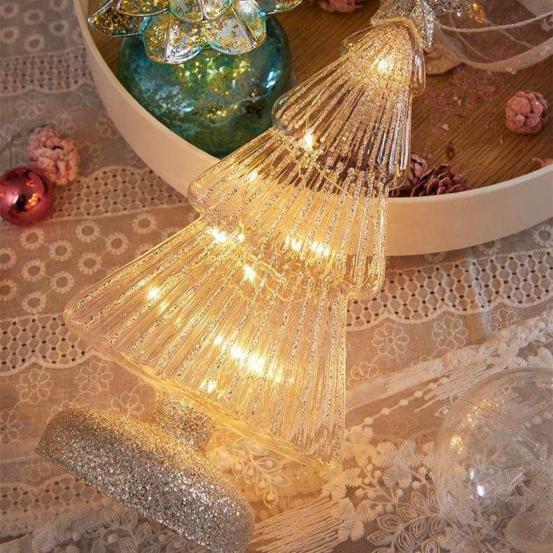 Christmas table decorations featuring a glittery glass Christmas tree with warm lights on a decorative table.