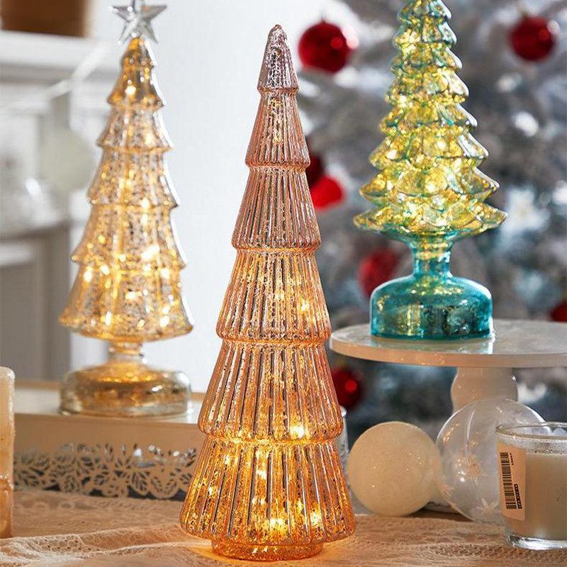 Christmas table decorations featuring geometric glass Christmas trees with lights in pink, silver, and green colors.