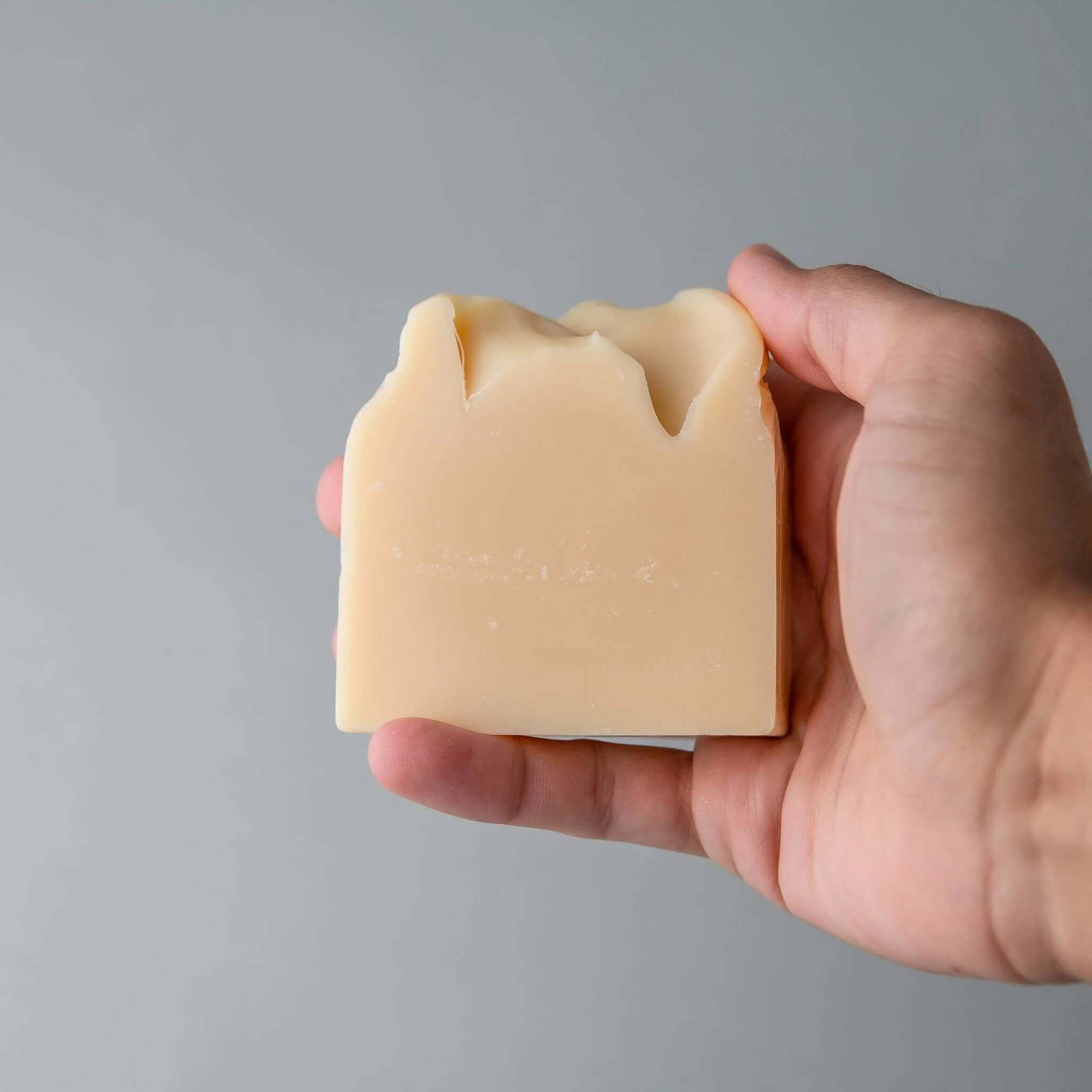 Hand holding natural beige menβs beard shampoo wash bar for gentle beard cleansing and nourishment