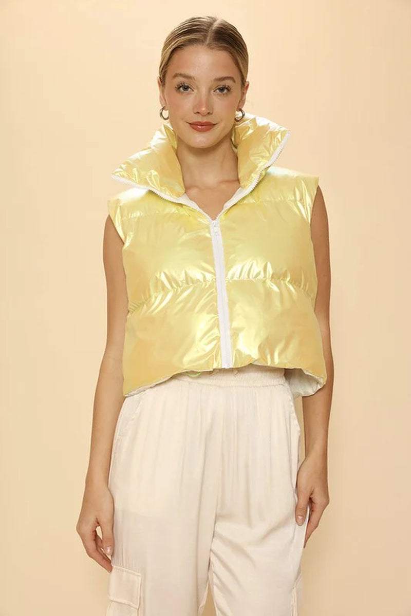 Cropped metallic puffer vest with mock neck, featuring a glossy shine, styled with high-waisted pants. Perfect for trendy looks.