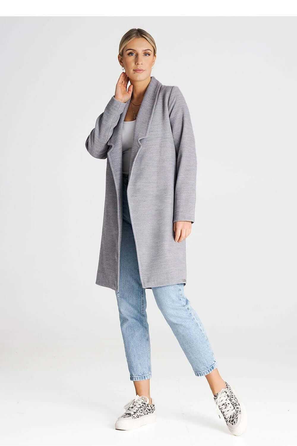 Woman wearing a minimalist gray buttoned midi coat with large collar and casual jeans.