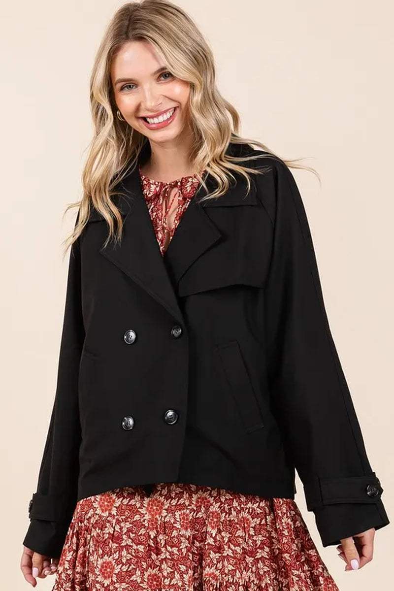 Woman wearing black double breasted trench coat jacket over floral dress