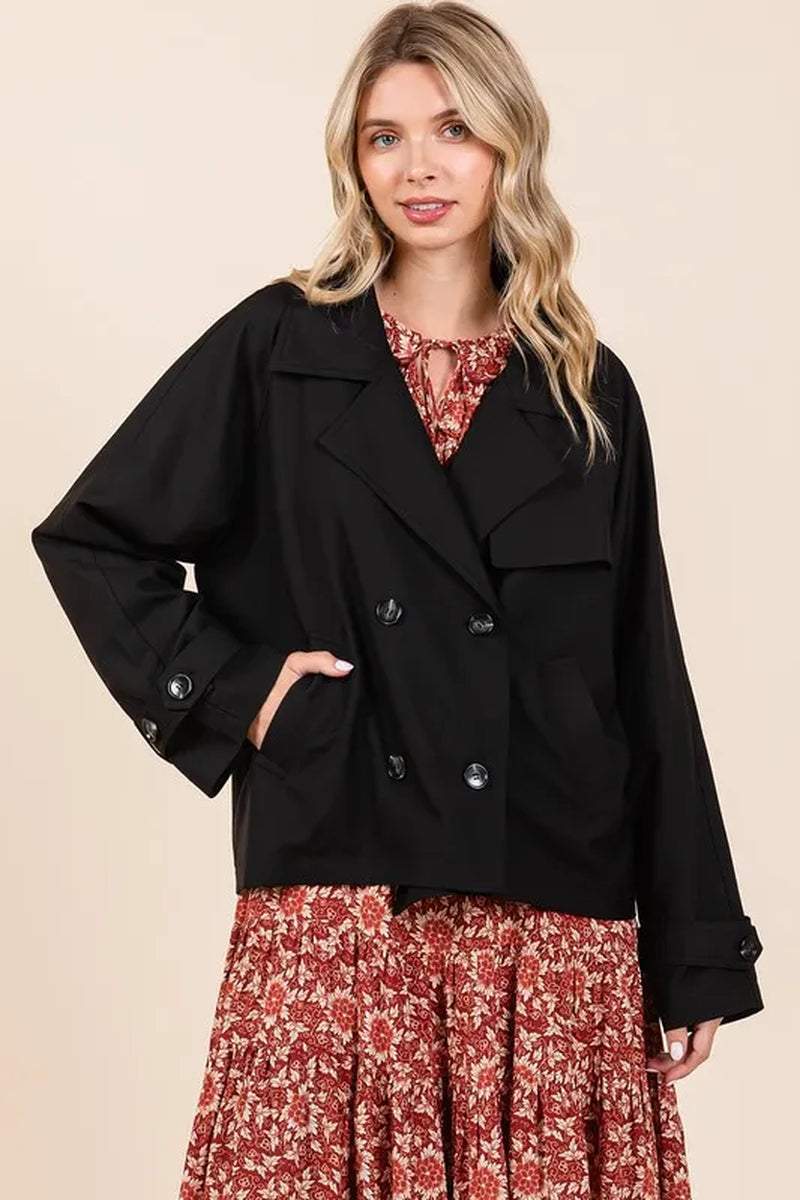 Woman wearing black double breasted trench coat jacket with long sleeves and button details over floral dress
