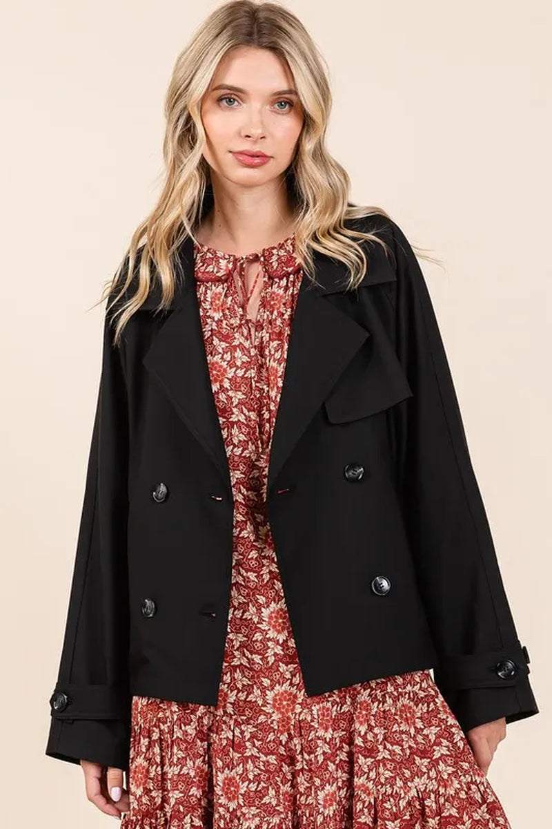 Woman wearing black double breasted trench coat over floral dress