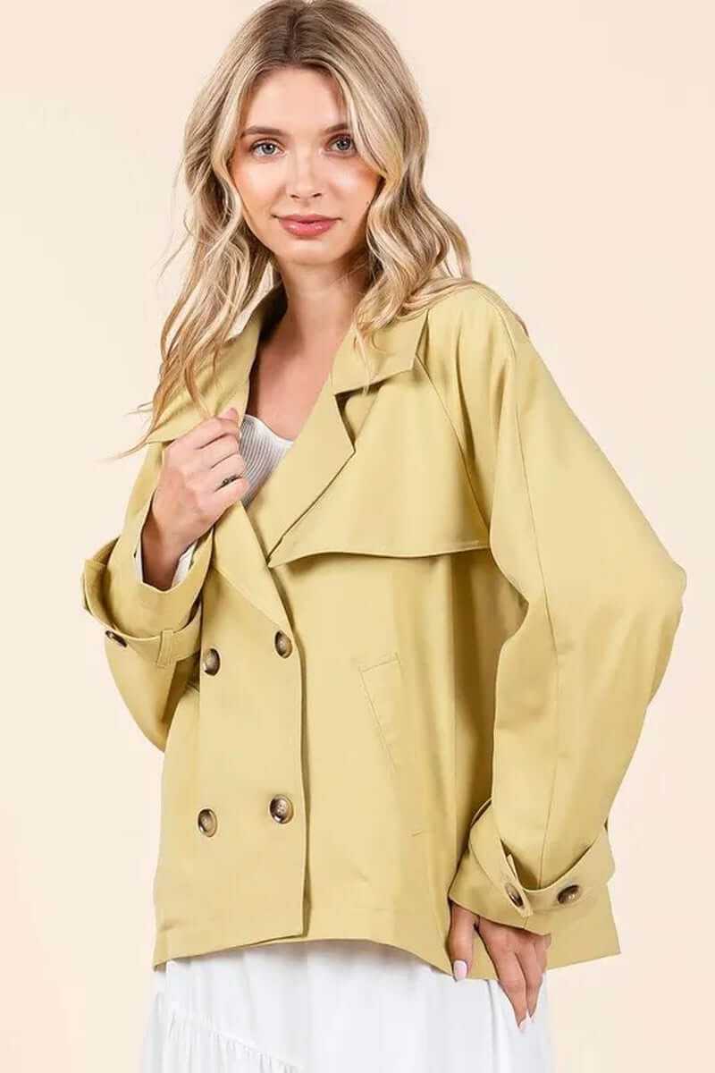 Woman wearing a stylish yellow double-breasted trench coat jacket with long sleeves, perfect for transitional weather.