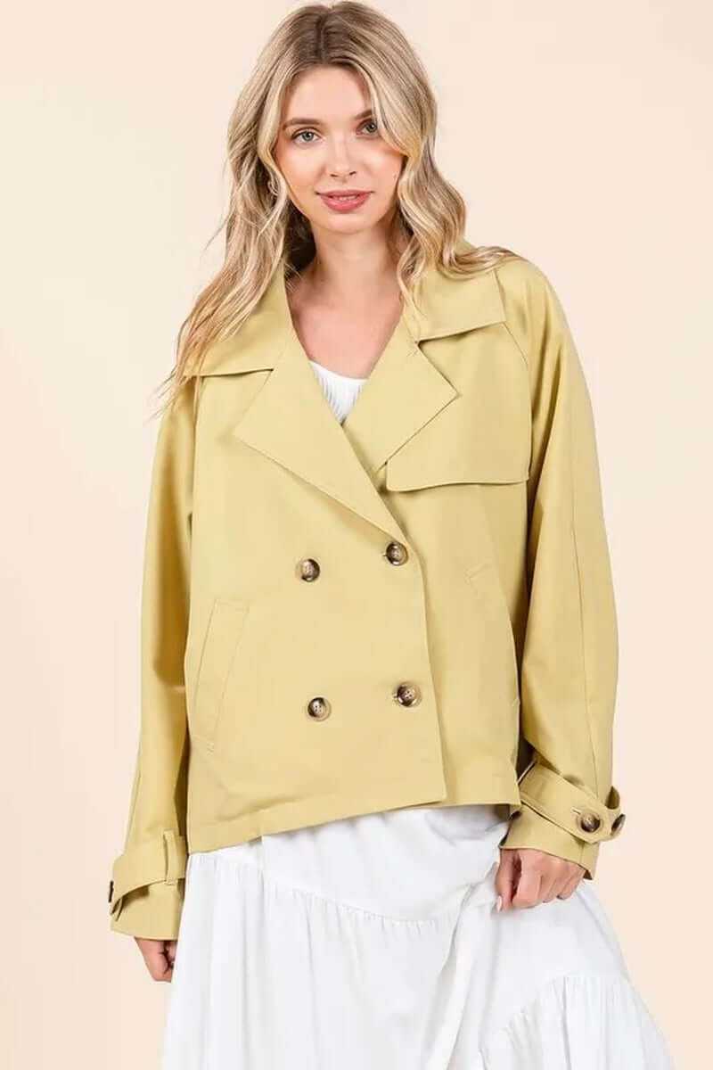Model wearing a yellow double-breasted long sleeve trench coat jacket, featuring elegant design and stylish look.