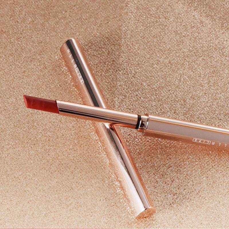 Moisturizing Cosmetics small tube lipstick in vintage red pear shade with sleek gold packaging on glittery background