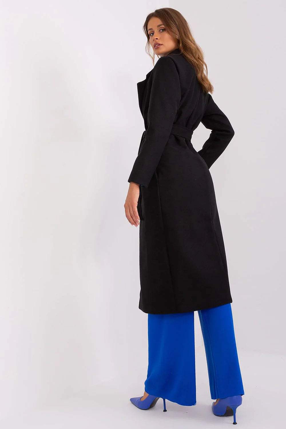 Model wearing the Och Bella Classic Belted Wool Coat, showcasing its sleek design and long cut, paired with blue wide-leg pants.