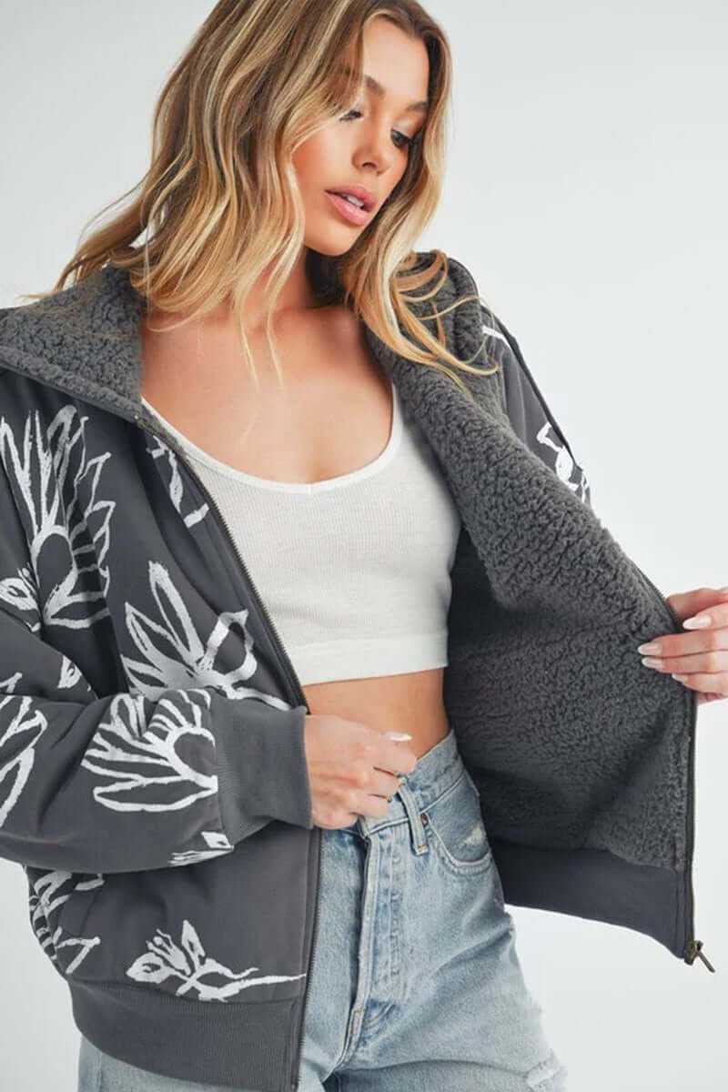Model showcasing the cozy Oita jacket with floral prints and soft sherpa lining, styled with a cropped top and jeans.